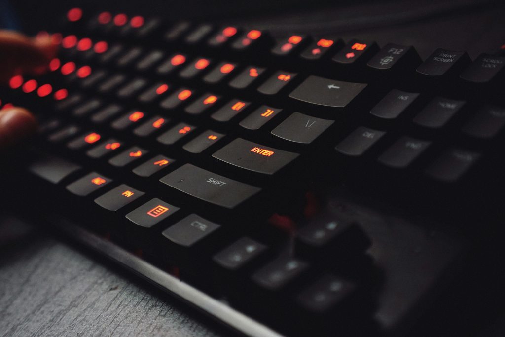 Detailed view of a gaming keyboard with backlit keys and glowing red lights.